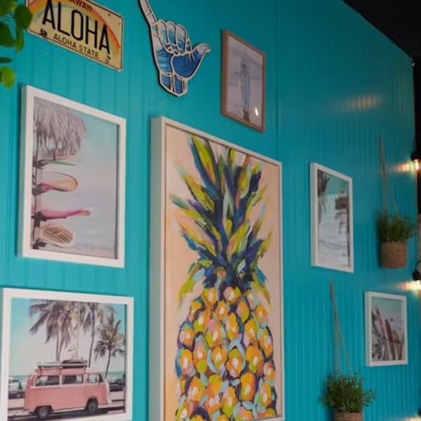 Hawaiian-themed wall decor with a pineapple painting, surfboards, and an "Aloha" license plate.